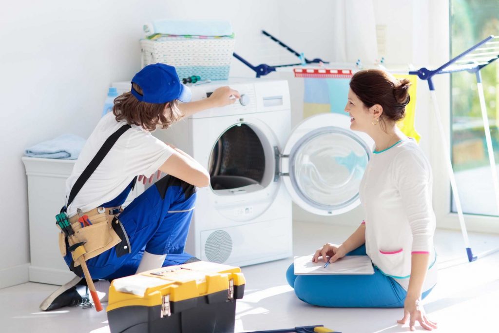 a technician repairing a washer while woman is watching - appliance repair service Mount Pleasant